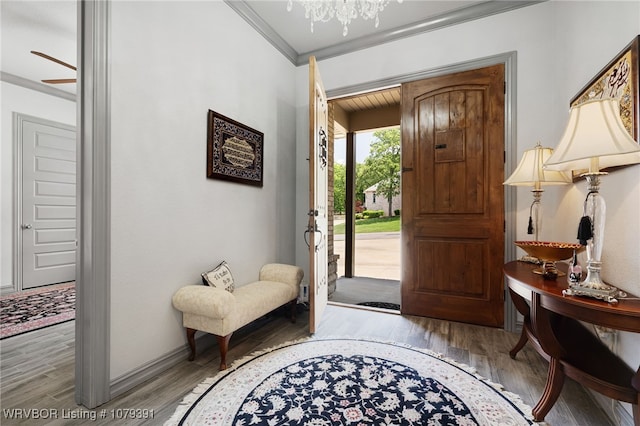 entryway with an inviting chandelier, wood finished floors, baseboards, and ornamental molding