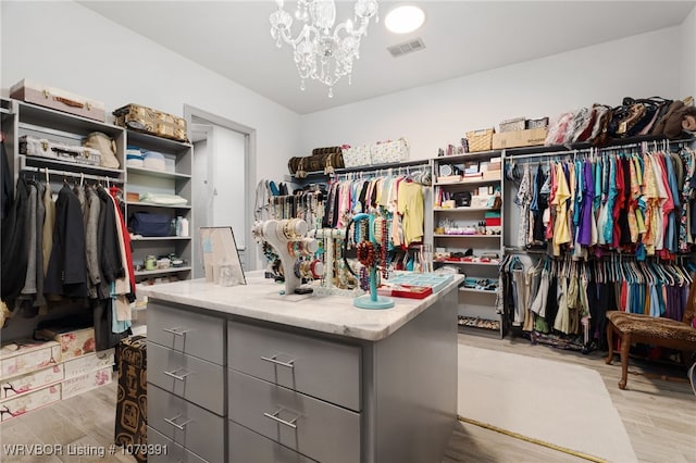 walk in closet with a notable chandelier, visible vents, and light wood-style floors