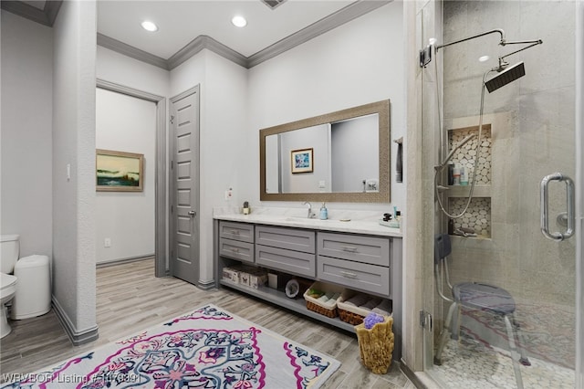 full bath featuring toilet, a stall shower, ornamental molding, wood finished floors, and vanity