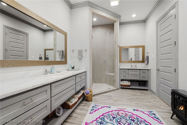 bathroom featuring a sink, wood finished floors, ornamental molding, and a shower stall