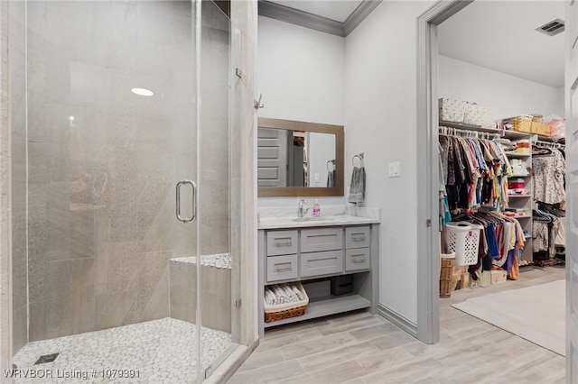 full bath with visible vents, a stall shower, vanity, crown molding, and a spacious closet