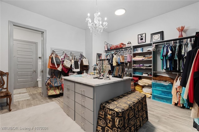 walk in closet featuring light wood finished floors and a chandelier