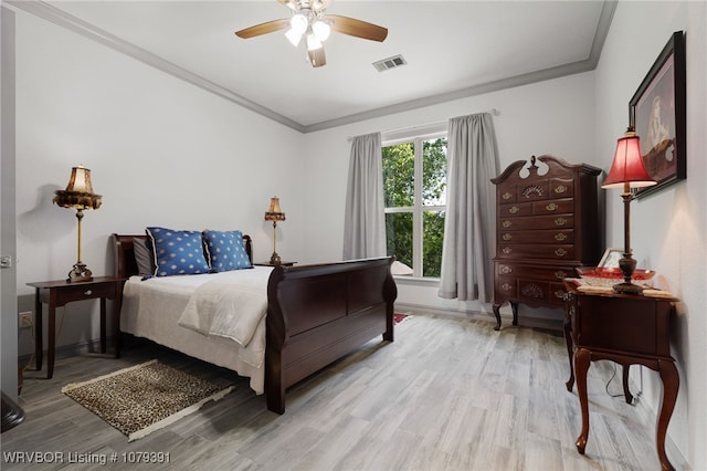 bedroom featuring a ceiling fan, light wood-style floors, visible vents, and ornamental molding