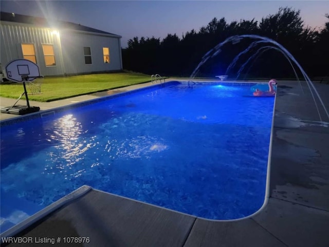 pool at dusk featuring a lawn and an outdoor pool