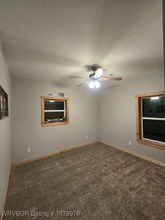 carpeted spare room featuring a textured ceiling, baseboards, and a ceiling fan