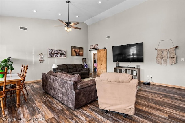 living area with visible vents, a ceiling fan, dark wood-type flooring, and a barn door