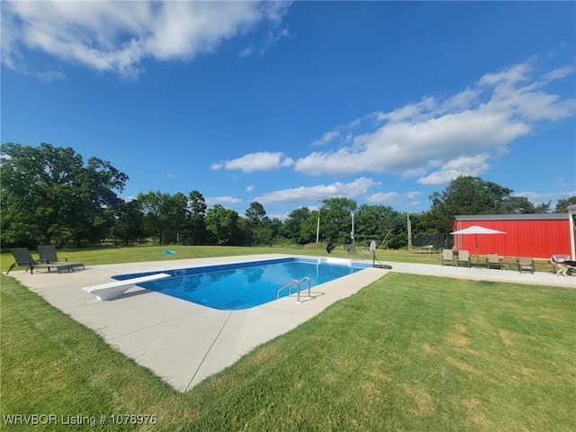 pool with a patio, a yard, and a diving board