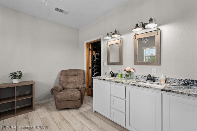 bathroom featuring double vanity, wood finished floors, visible vents, and a sink