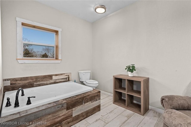 full bathroom featuring wood finished floors, toilet, a bath, and baseboards