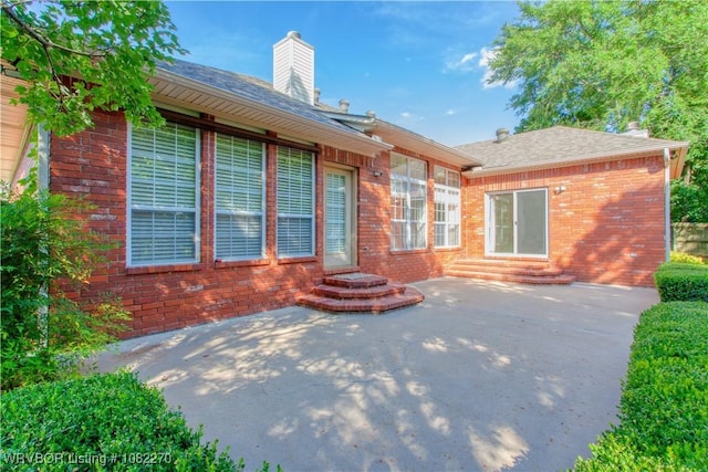 2112 Rannoch Trce, Fort Smith, AR 72908 - back of house featuring brick siding, a chimney, a patio, a shingled roof, and entry steps