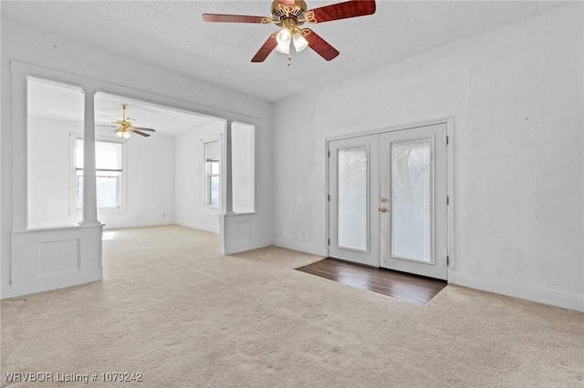 carpeted entryway with a textured ceiling, french doors, and a ceiling fan