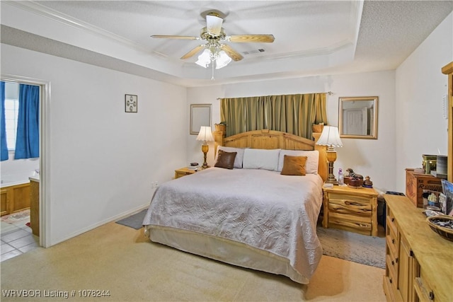 bedroom featuring ensuite bathroom, a textured ceiling, a raised ceiling, ceiling fan, and crown molding