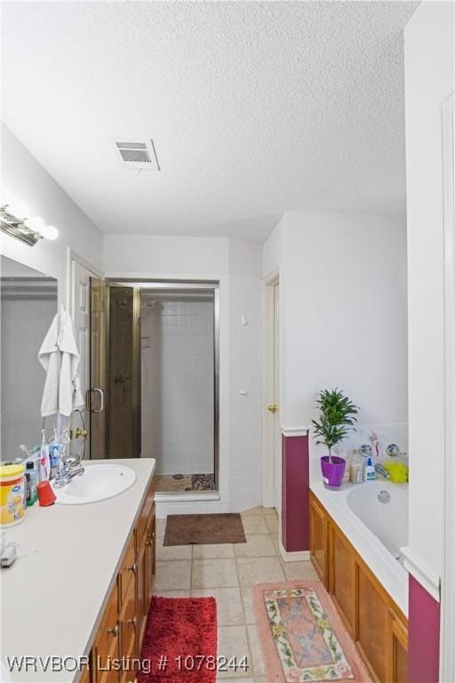 bathroom with tile patterned floors, vanity, separate shower and tub, and a textured ceiling