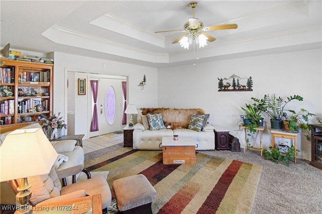 carpeted living room featuring ceiling fan, a raised ceiling, and crown molding