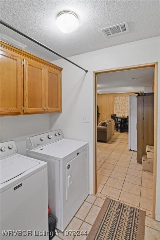 laundry area featuring light tile patterned flooring, cabinets, independent washer and dryer, and a textured ceiling