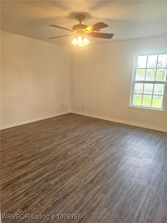 spare room featuring baseboards, ceiling fan, and dark wood-style floors