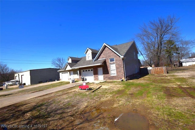 view of front facade with an attached garage, dirt driveway, fence, and brick siding