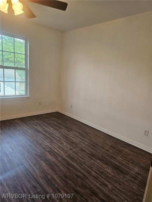 empty room with baseboards, dark wood finished floors, and ceiling fan