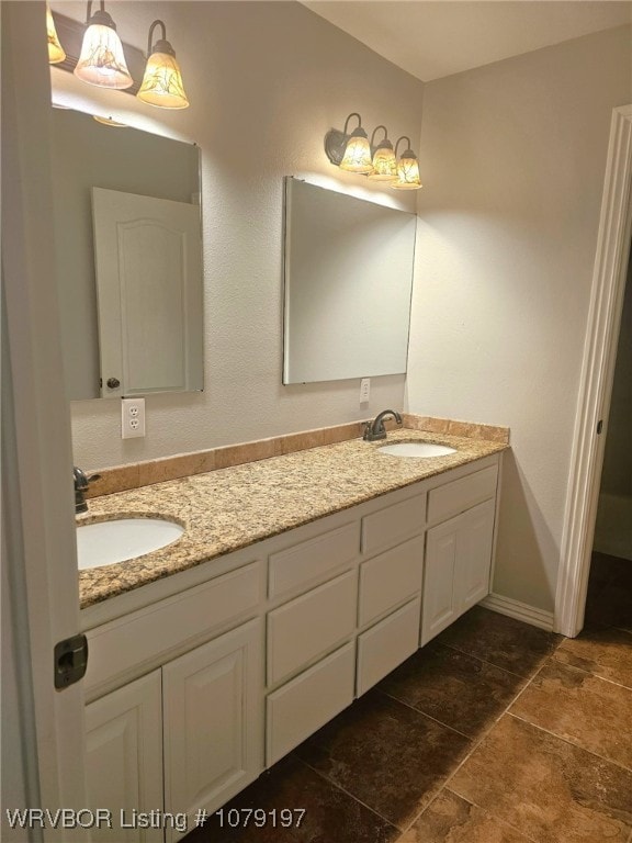 full bath featuring double vanity, a sink, and stone finish flooring