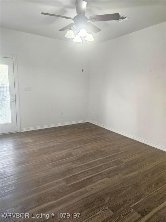 unfurnished room with baseboards, dark wood finished floors, and ceiling fan
