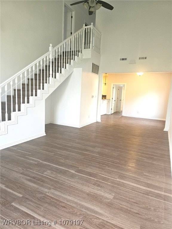 unfurnished living room with a ceiling fan, a high ceiling, visible vents, and wood finished floors