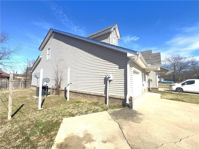 view of property exterior featuring fence, an attached garage, and driveway