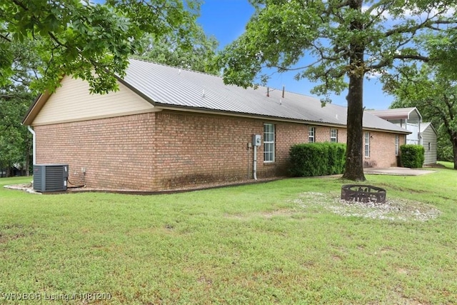 42735 Timber Ridge Rd, Howe, OK 74940 - back of property featuring an outdoor fire pit, brick siding, a lawn, and central AC unit