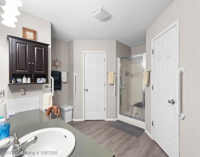 42735 Timber Ridge Rd, Howe, OK 74940 - bathroom with a stall shower, wood finished floors, a textured ceiling, baseboards, and vanity