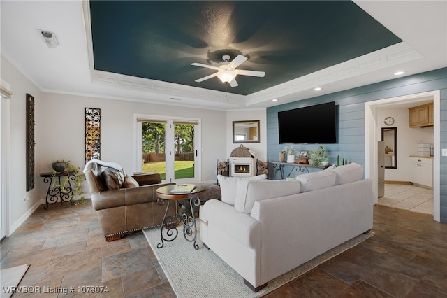 living room featuring a tray ceiling, ceiling fan, and ornamental molding