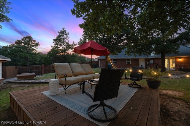 deck at dusk with outdoor lounge area and a lawn