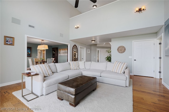 living room featuring hardwood / wood-style floors, ceiling fan with notable chandelier, and high vaulted ceiling