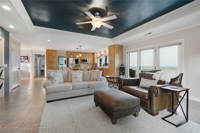 tiled living room featuring a raised ceiling, ceiling fan, and crown molding