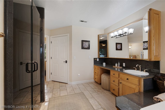 bathroom featuring decorative backsplash, vanity, and a shower with shower door