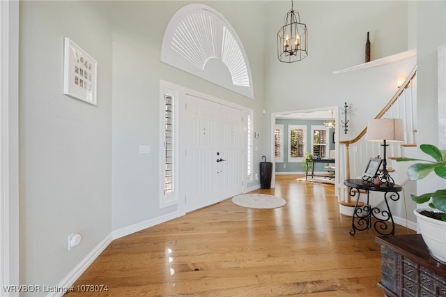 entrance foyer featuring an inviting chandelier, a high ceiling, and light wood-type flooring