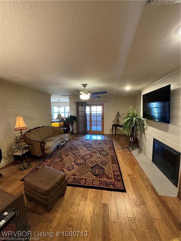 2925 Gary St Unit 12, Fort Smith, AR 72901 - living area featuring a ceiling fan, a textured ceiling, a tiled fireplace, and wood finished floors
