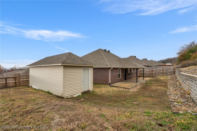 rear view of house featuring a yard, brick siding, a patio, and a fenced backyard