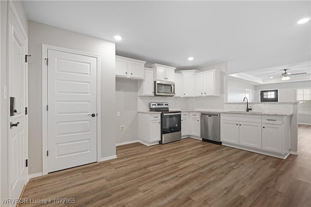 kitchen featuring light stone counters, stainless steel appliances, ceiling fan, dark wood-type flooring, and white cabinetry