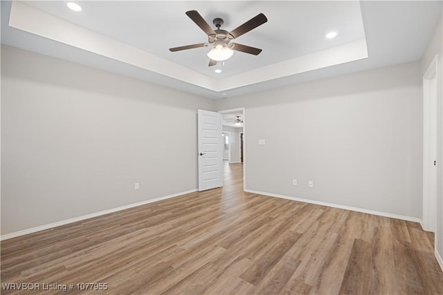 spare room with hardwood / wood-style flooring, a raised ceiling, and ceiling fan