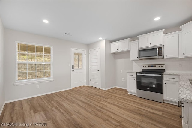 kitchen with white cabinets, decorative backsplash, light stone countertops, and appliances with stainless steel finishes