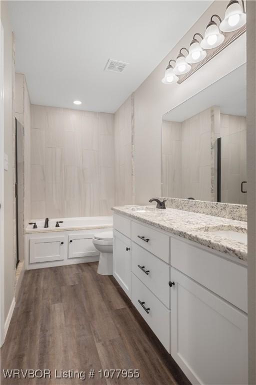 full bathroom featuring wood-type flooring, vanity, shower with separate bathtub, and toilet