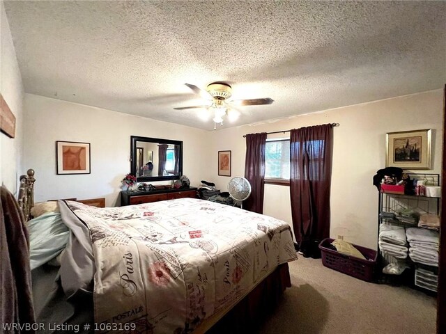 bedroom with ceiling fan, carpet floors, and a textured ceiling