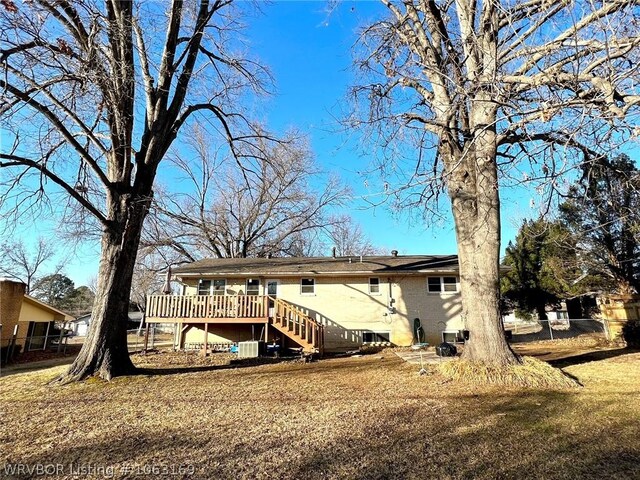 back of house with a deck, cooling unit, and a lawn