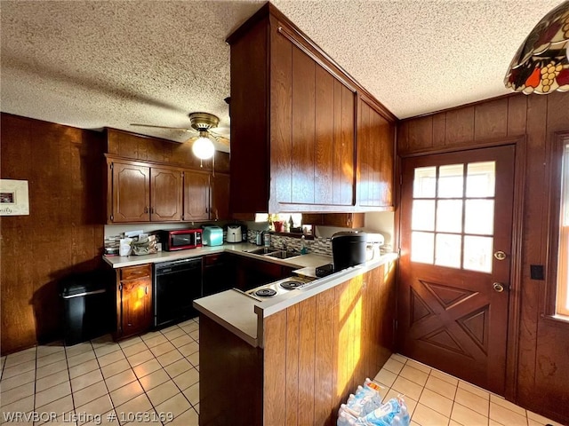 kitchen featuring sink, kitchen peninsula, wooden walls, light tile patterned floors, and black appliances