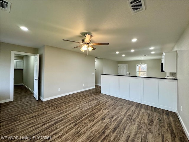 interior space with ceiling fan with notable chandelier, dark hardwood / wood-style flooring, and sink