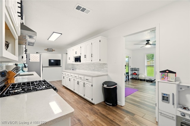9010 Skypark Dr, Fort Smith, AR 72903 - kitchen featuring white microwave, white cabinets, a ceiling fan, light wood finished floors, and backsplash