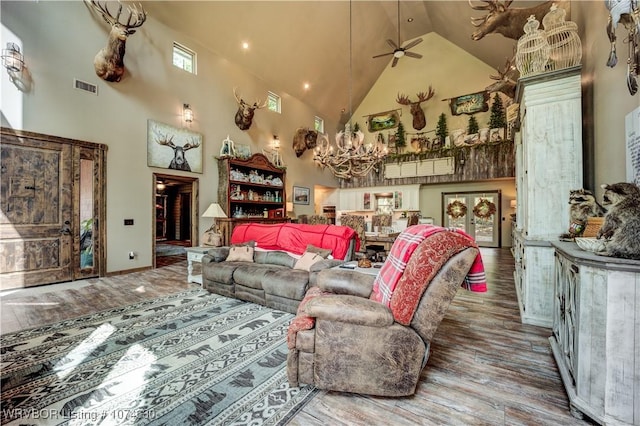 living room featuring ceiling fan with notable chandelier, hardwood / wood-style flooring, and high vaulted ceiling