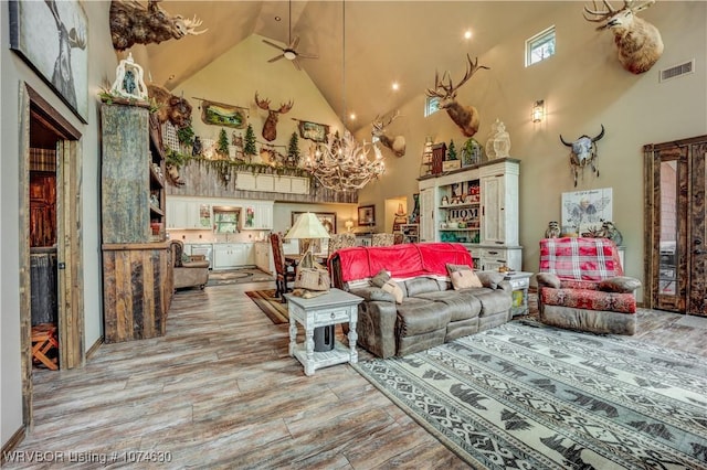 living room with ceiling fan with notable chandelier and high vaulted ceiling