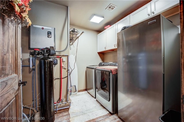 laundry room featuring washer and clothes dryer, cabinets, and light hardwood / wood-style flooring