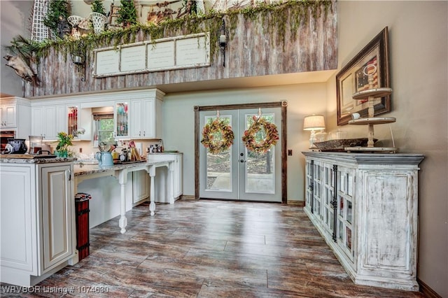 bar with white cabinetry, french doors, a healthy amount of sunlight, and light stone counters