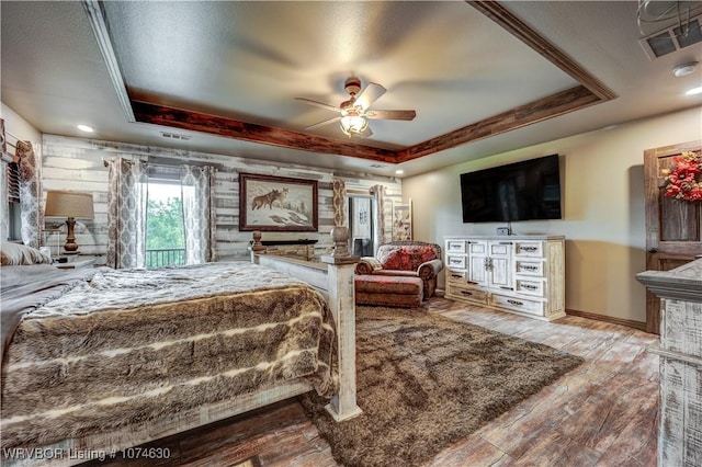 bedroom with ceiling fan, a raised ceiling, and wood-type flooring